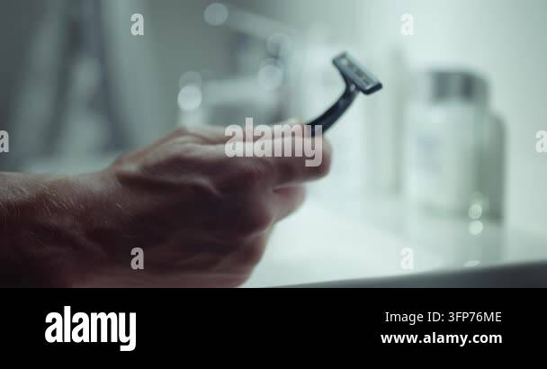Closeup of male hand holding blue disposable razor against bright ...