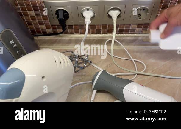 Hand unplugging unused electrical appliances from wall outlets, leaving ...