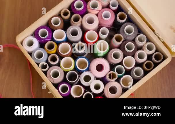 Multicolored sewing threads lie in wooden box. person body part hand ...
