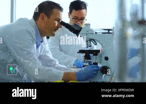 Two researchers leaning into scope, placing slide at lab, causing teal ...