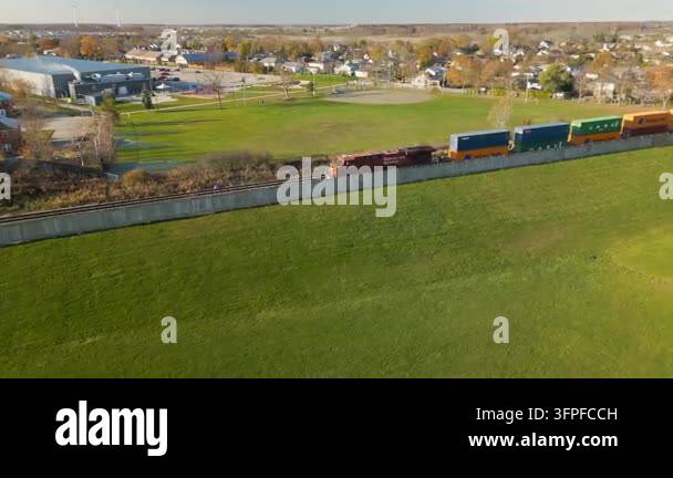 Clea Rsky Background Train moving past vast green field with residential homes in background ...