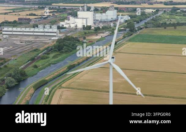 Wind turbine blades spin continuously in a golden field on a bright day ...