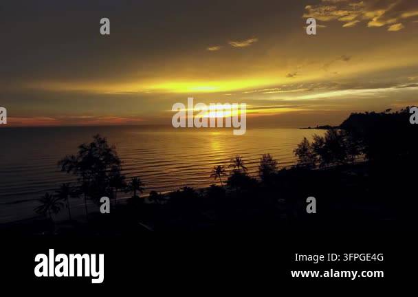 aerial drone view capture of a golden tropical sunset casting warm ...