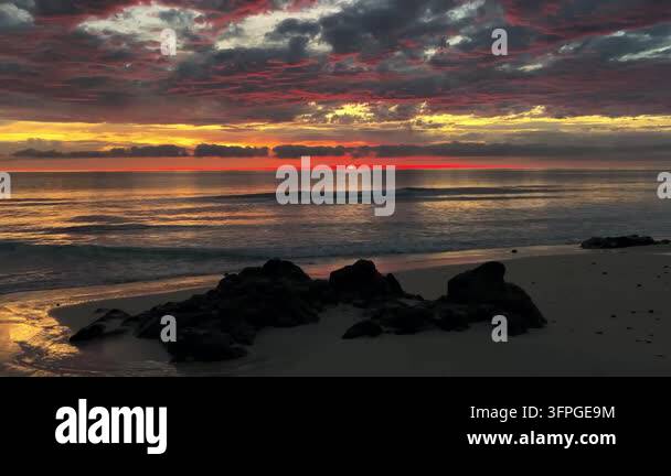 dramatic sunset over ocean beach with dark rocks on sand nature ...