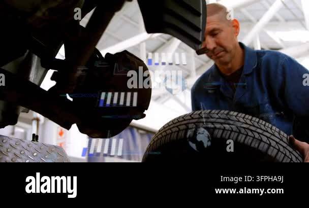Auto mechanic inspecting hub, lifting and aligning rim onto studs with ...