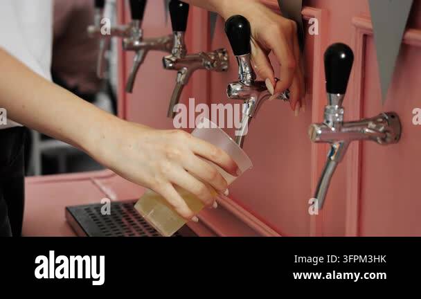 Light Tapping Close-up of woman opening a beverage tap and pouring a light draft ...