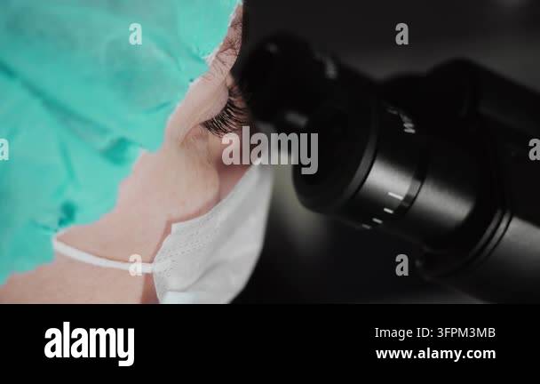 Close-up of a female laboratory scientist looking through a microscope ...