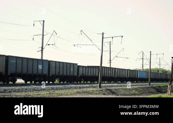 Overhead Railing Long freight train with open cargo wagons traveling along an ...