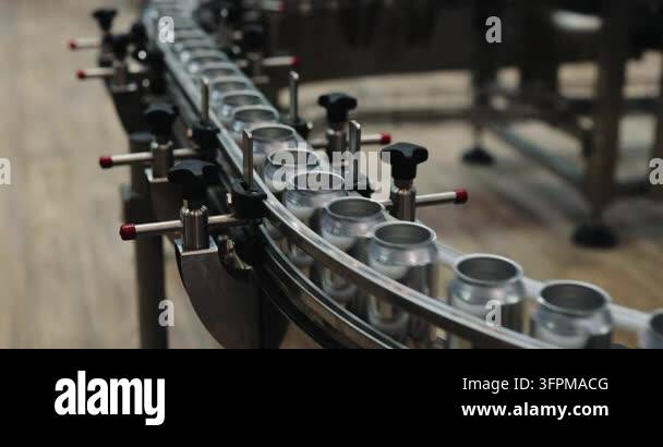 Empty metal cans travel around curved conveyor inside automated ...
