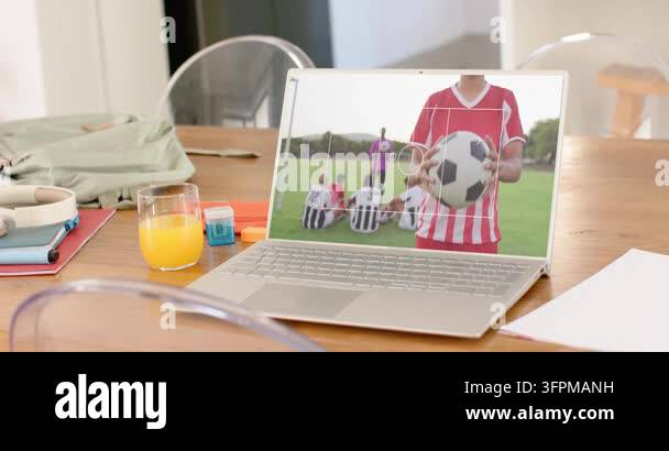 Male soccer player holding ball on laptop at home table, focus marker ...