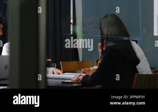 Left person pointing documents, causing AR icons on glass while team ...