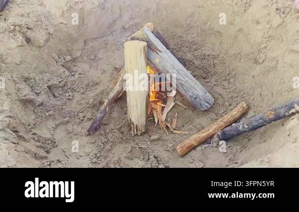 Sandy Fire Small campfire burning between wooden logs in a sandy fire pit Stock ...