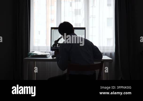 Scientist silhouette working at a desk with microscope and computer ...