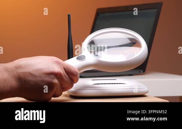 Hand holding a magnifying glass over a white wireless router ...