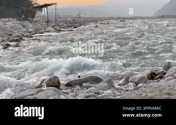 Simple Sign File A wide shot of a fast-flowing river with rocky banks and a simple ...