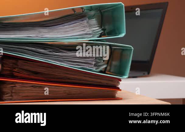 Stacked ring binders overflowing with papers and reports, illustrating ...