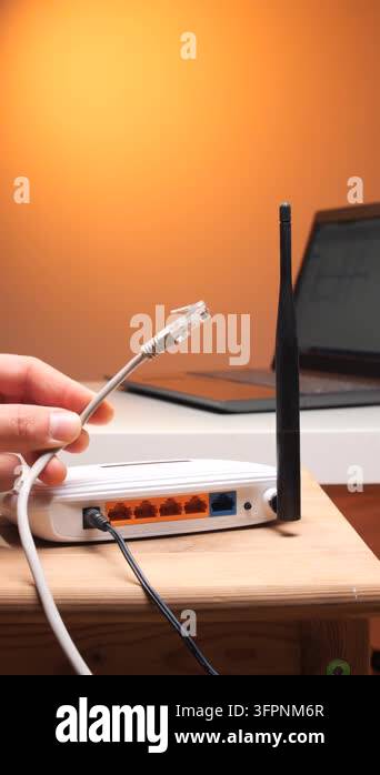 Vertical video persons hand connecting an ethernet cable to a white ...