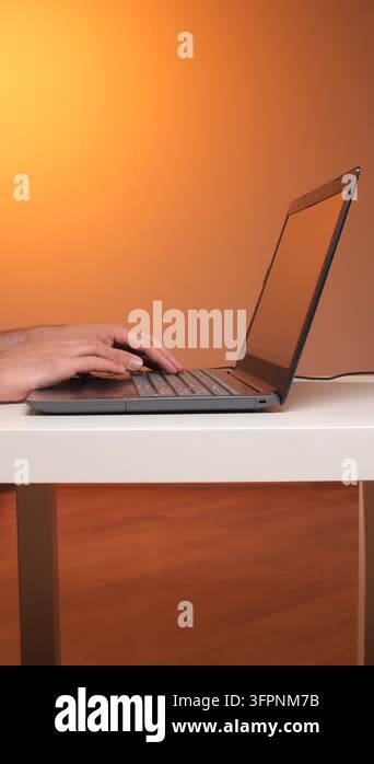 Vertical video persons hands typing on a laptop keyboard at a desk ...