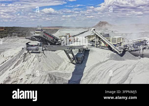 Working In Process Machines work in a quarry to move and process materials. Dust and piles ...