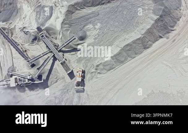Heavy machinery works in a quarry to extract stone materials. The ...