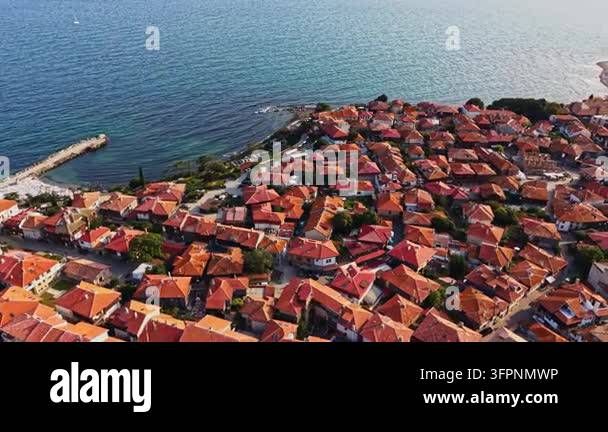 A coastal town with many red-tiled roofs. The town is by the sea and ...