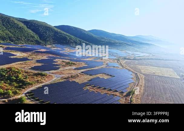 Clea Rsky Background Rows of solar panels cover the land in a valley. Mountains rise in the ...