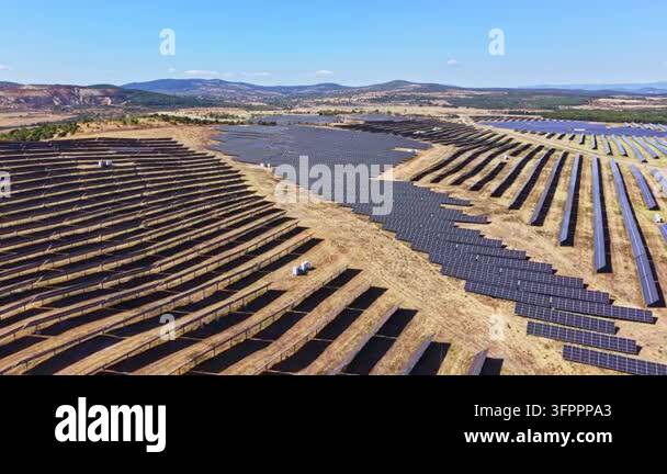 Large Area A large solar farm stretches across a flat landscape with numerous rows ...