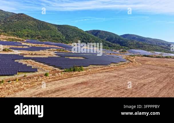 Large Area Solar panels are set up across a large field in a hilly area on a clear ...