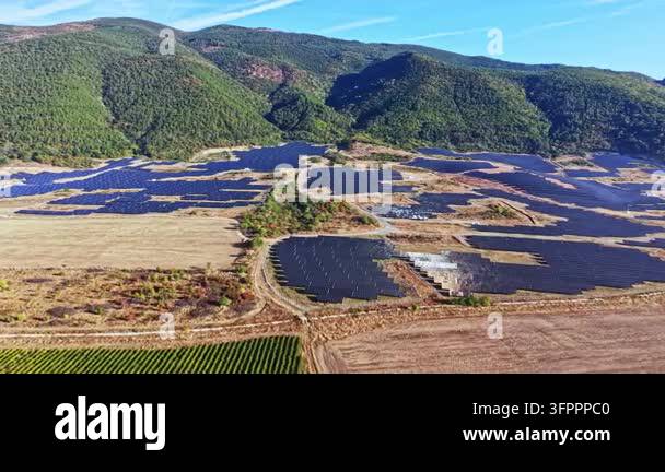 Rows of solar panels are placed across a wide expanse of land ...