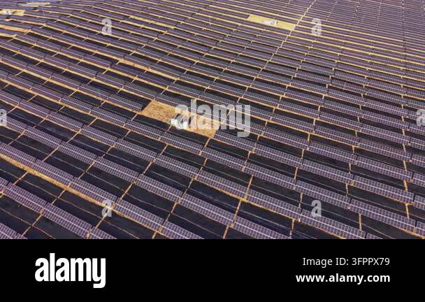Workers check the solar panels installed in rows at a solar farm on a ...