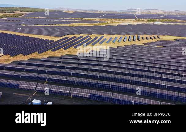 Large Area Rows of solar panels stretch across a wide area under a clear sky. This ...