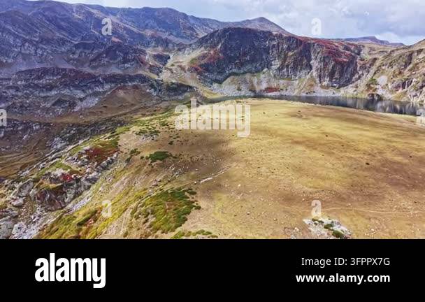Large Area A large grassy area bordered by mountains and a lake in a remote region ...