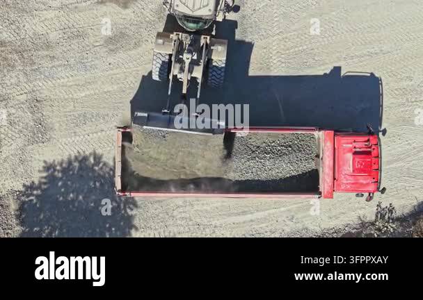 Loading Vehicle Vector A large machine loads granite onto a red truck at a granite quarry ...