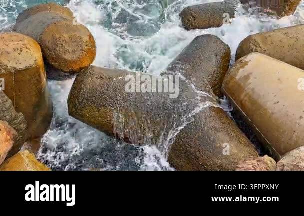 Large Interaction Model Water flows over large rocks in a harbor setting. Waves crash against ...