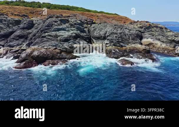 Html Olors Waves hit the rocky shore near the coast. The sun shines brightly in ...