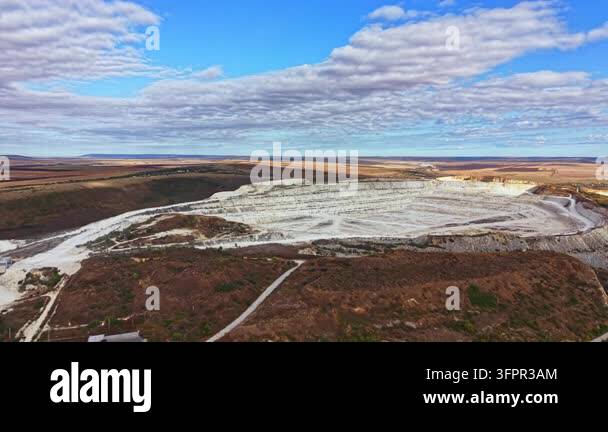 Large Area A large open pit mine is visible in a rural area with clear blue skies ...