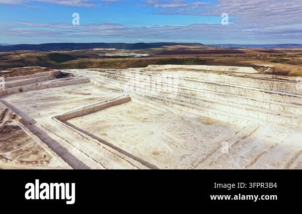 Large Area Mining activity occurs in a large open pit area showing layers of earth ...