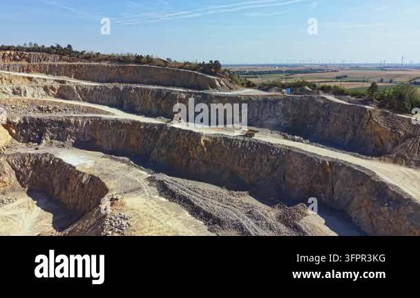 Large Area Heavy machinery operates in a large quarry as workers move earth and ...