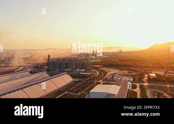 Large Area The sun sets over a large industrial area. Factories and silos are ...