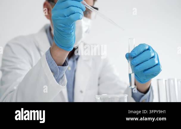 Scientist wearing personal protective equipment performing a liquid ...