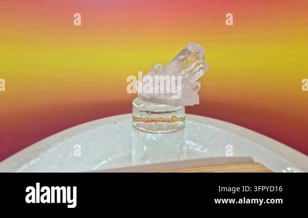 Close-up of a clear quartz crystal cluster on a glass stand, with water ...