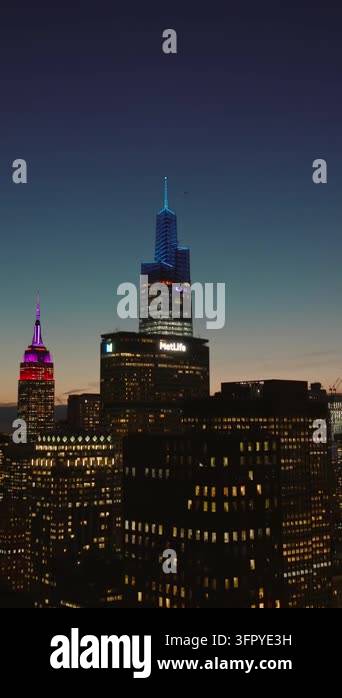 Vertical video: Descending footage of high rise buildings with lighted ...