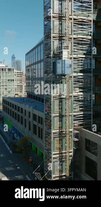 Vertical video: Rising shot tracking of construction lift moving up ...