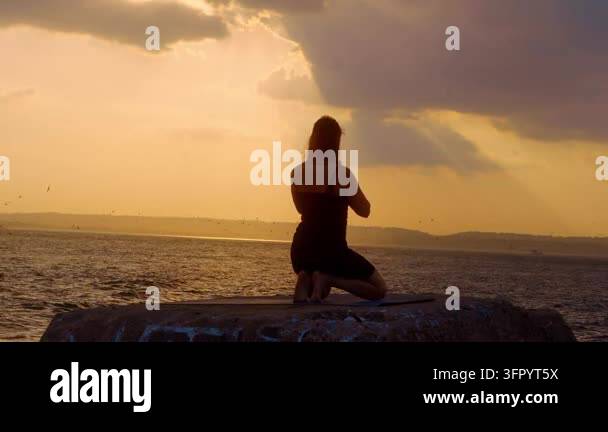 Pose Rasining Hand Woman reaching arm up in kneeling yoga pose outdoors. Back view ...