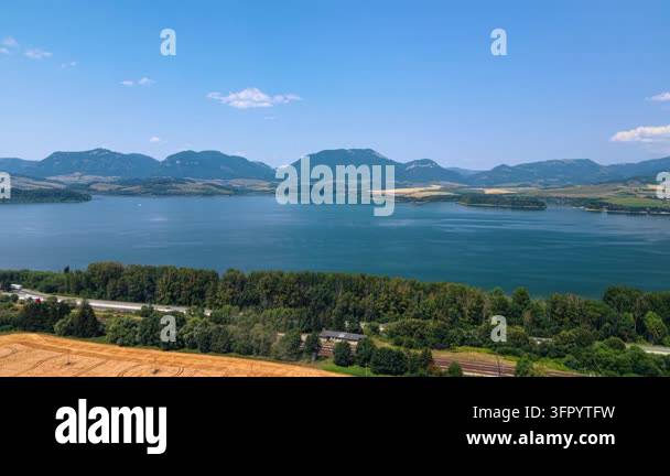 Mountain lake bordered by forest and fields in Slovakia. Blue water ...
