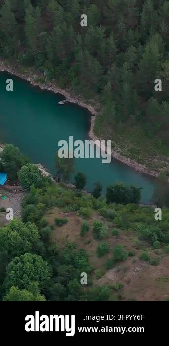 Aerial view of a narrow turquoise lake bordered by dense forest, rocky ...