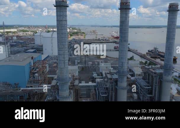 High angle drone footage shows tall smoke stacks at a large industrial ...