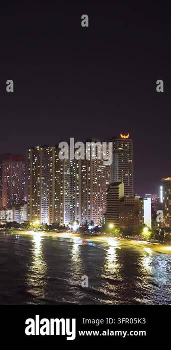 Waterfront High Rises Illuminated high-rise buildings line a waterfront at night, with lights ...
