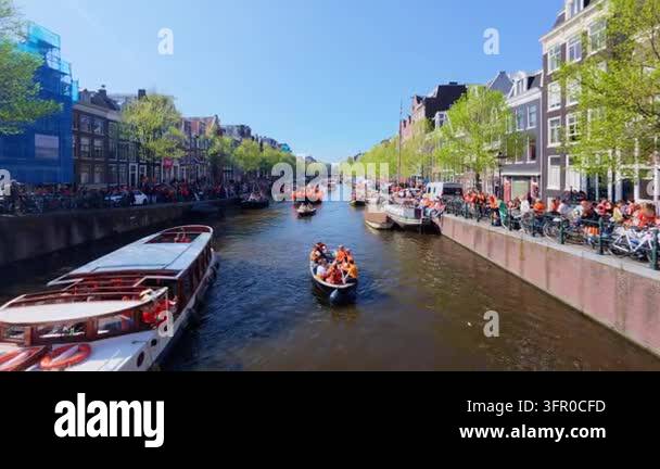 Kings Day celebration on a tree lined canal with open boats full of ...
