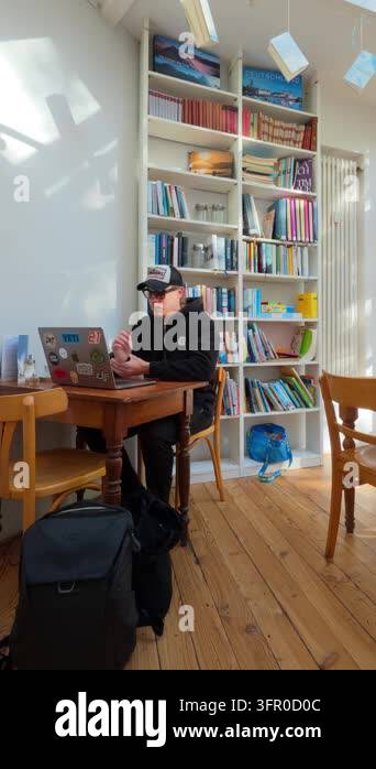 Decatur Library Shooting Static vertical shot of a young man in a cap and sunglasses working on ...